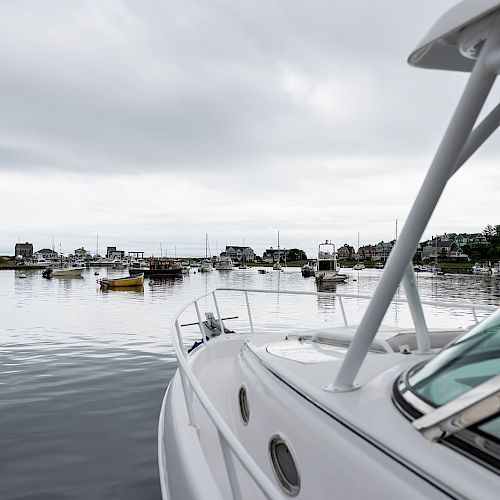 A marina with various boats on a calm body of water under a cloudy sky, with a close-up of a sleek white boat in the foreground ending the sentence.