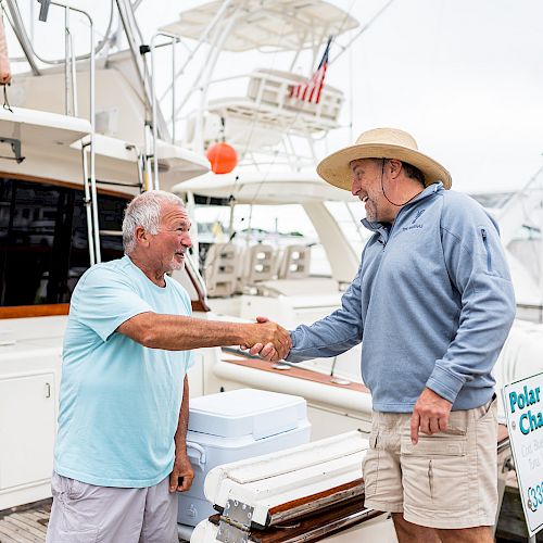 Two men are shaking hands on a boat dock next to a sign that reads 