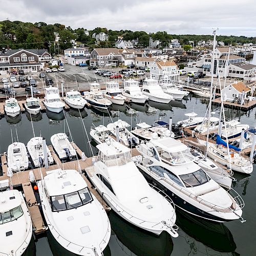 This image depicts a marina filled with various boats and yachts docked, along with buildings and houses in the background by the waterfront.