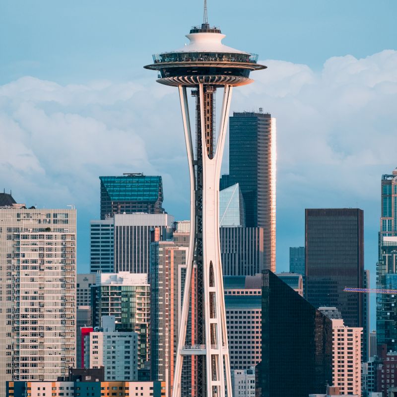 The image features the Space Needle in Seattle with a backdrop of the city's skyscrapers and a partly cloudy sky in the background.