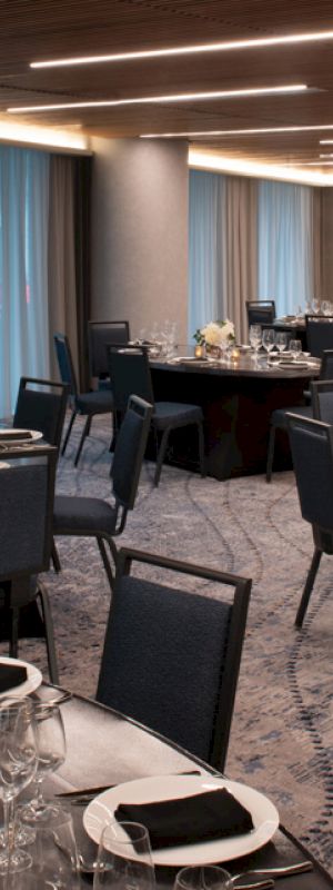 The image shows an elegantly set dining room with neatly arranged tables and chairs, ready for a formal event or banquet.