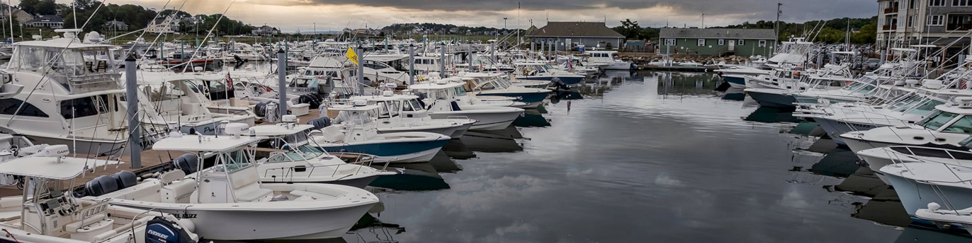 A marina filled with docked boats under a partly cloudy sky during sunset, creating a serene and picturesque scene.